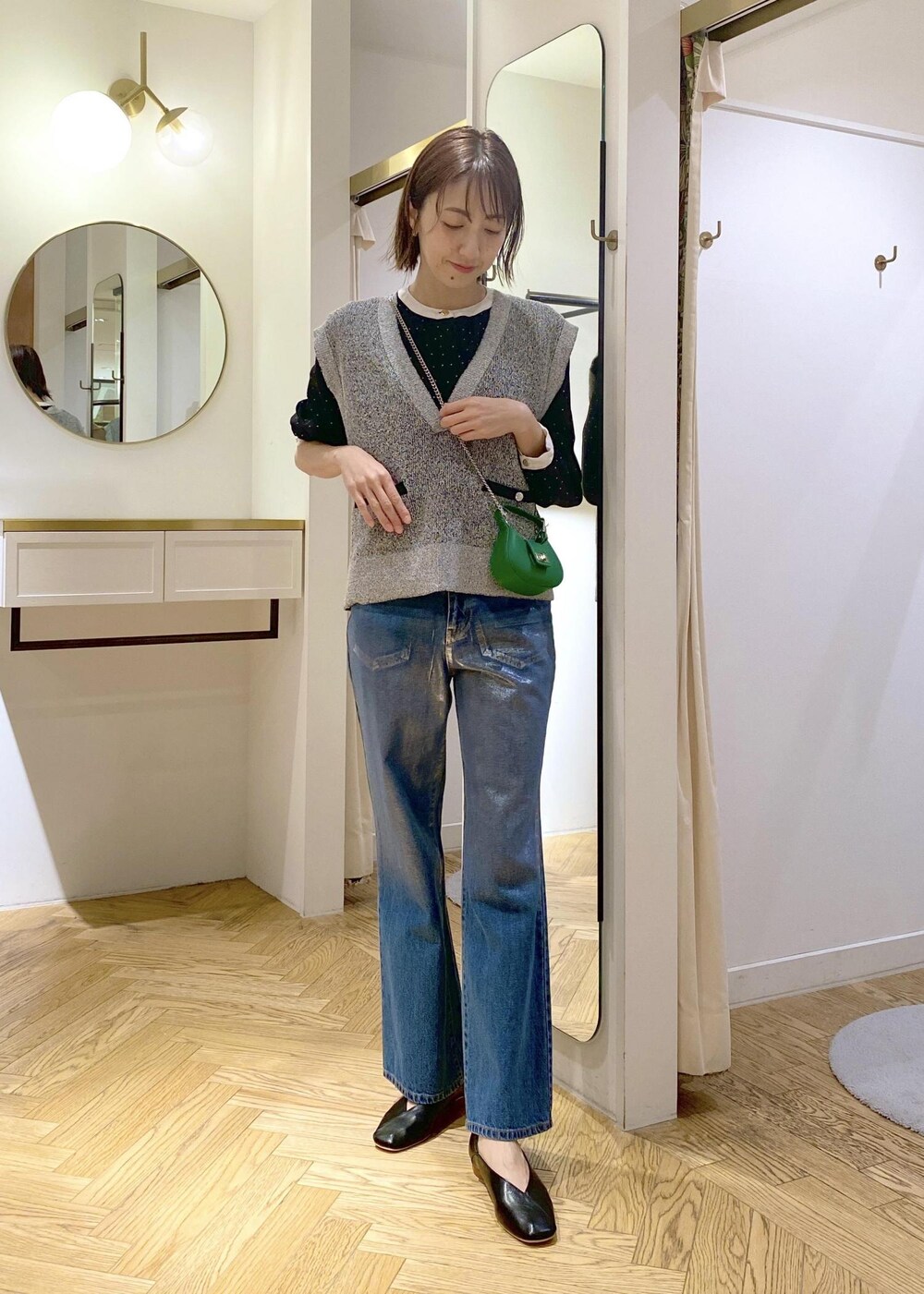 ブラック系のパンプス、ブルー系のデニムパンツ、ブラック系のベストを着用したレディースの春コーディネートの4枚目の写真