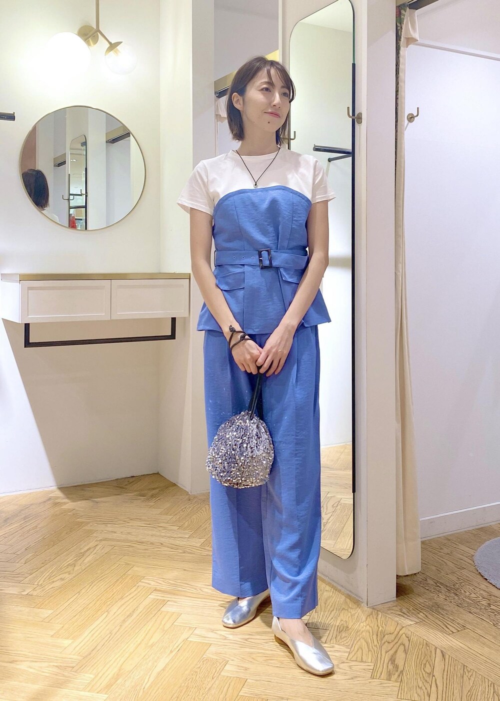 シルバー系のハンドバッグ、シルバー系のパンプス、ブルー系のTシャツ/カットソーを着用したレディースの春コーディネートの5枚目の写真