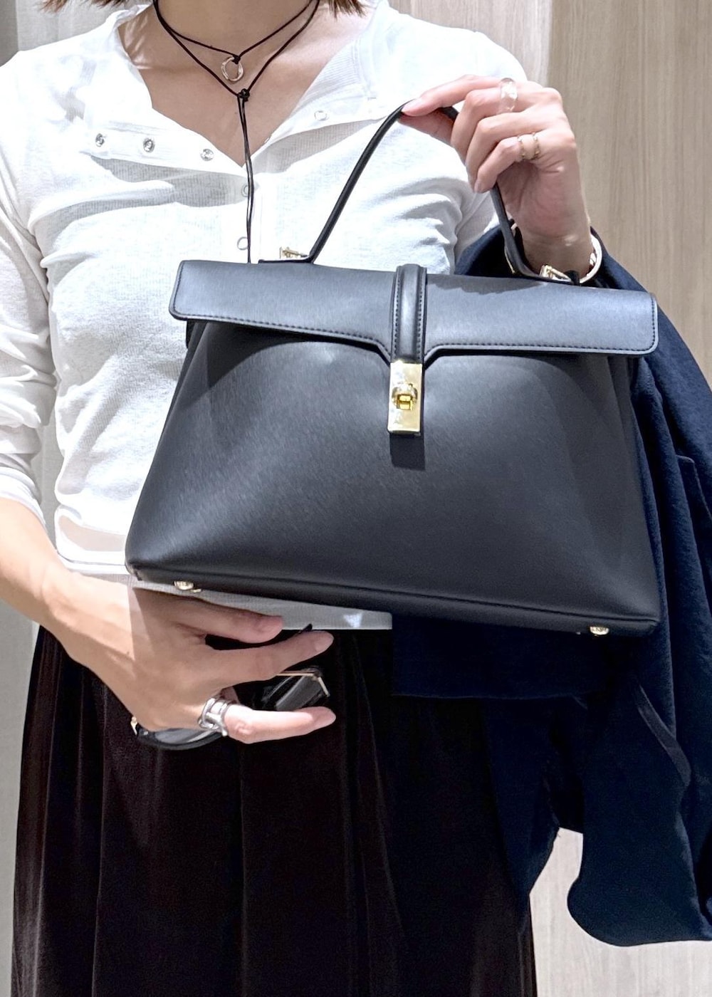 ブラック系のハンドバッグ、ブルー系のテーラードジャケット、ホワイト系のTシャツ/カットソーを着用したレディースの夏コーディネートの8枚目の写真