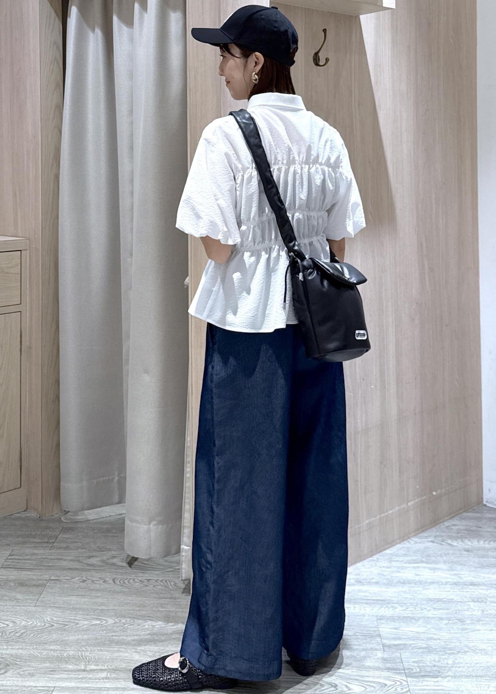 ブラック系のショルダーバッグ、ブラック系のパンプス、ブルー系のデニムパンツを着用したレディースの夏コーディネートの4枚目の写真