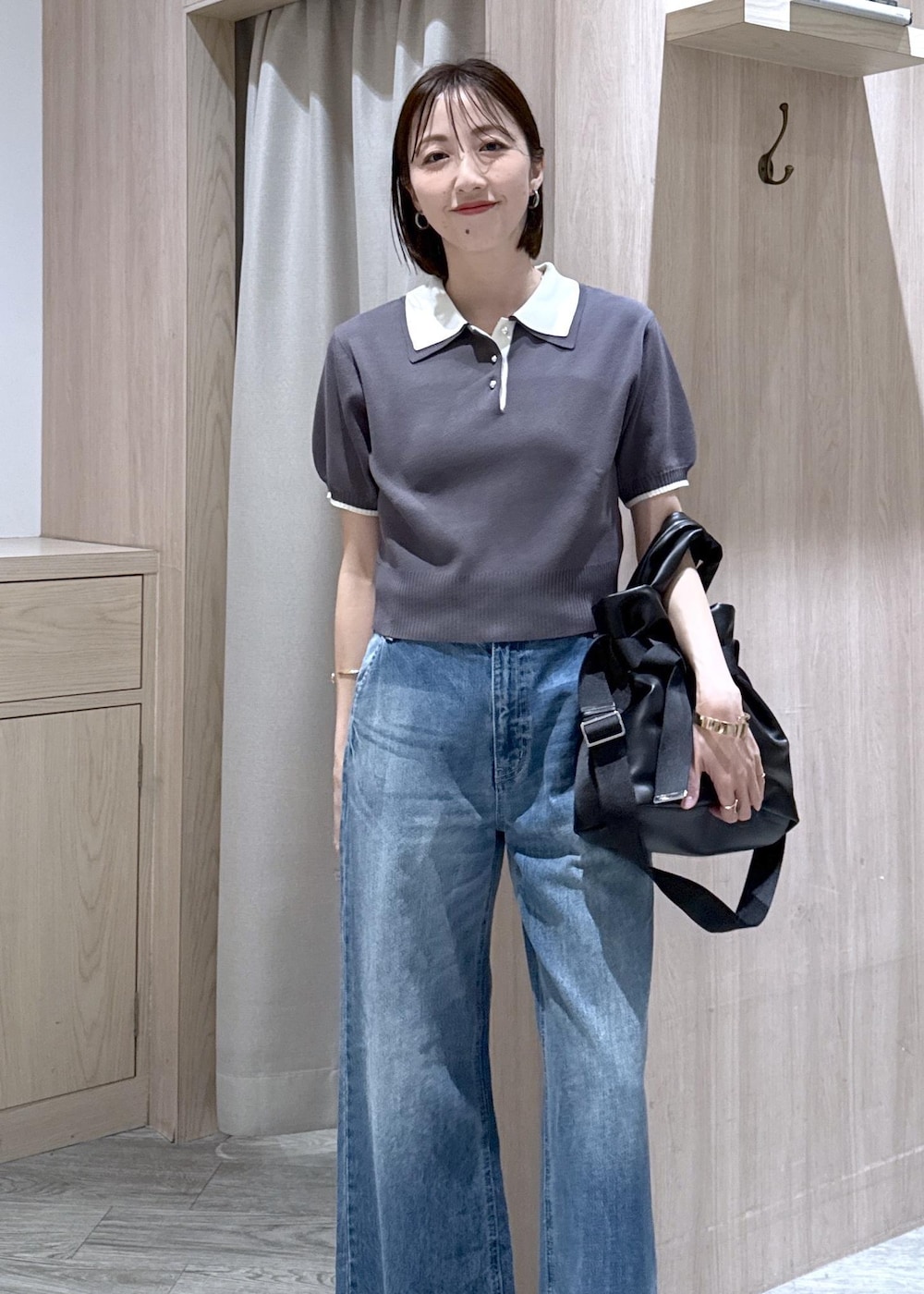 ホワイト系のキャミソール、ブラック系のトートバッグ、ブルー系のデニムパンツを着用したレディースの春コーディネートの3枚目の写真