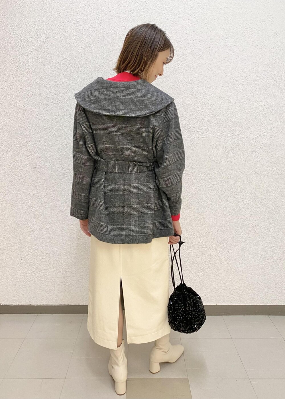 ホワイト系のスカート、ブラック系のその他アウター、ブラック系のハンドバッグを着用したレディースの冬コーディネートの2枚目の写真