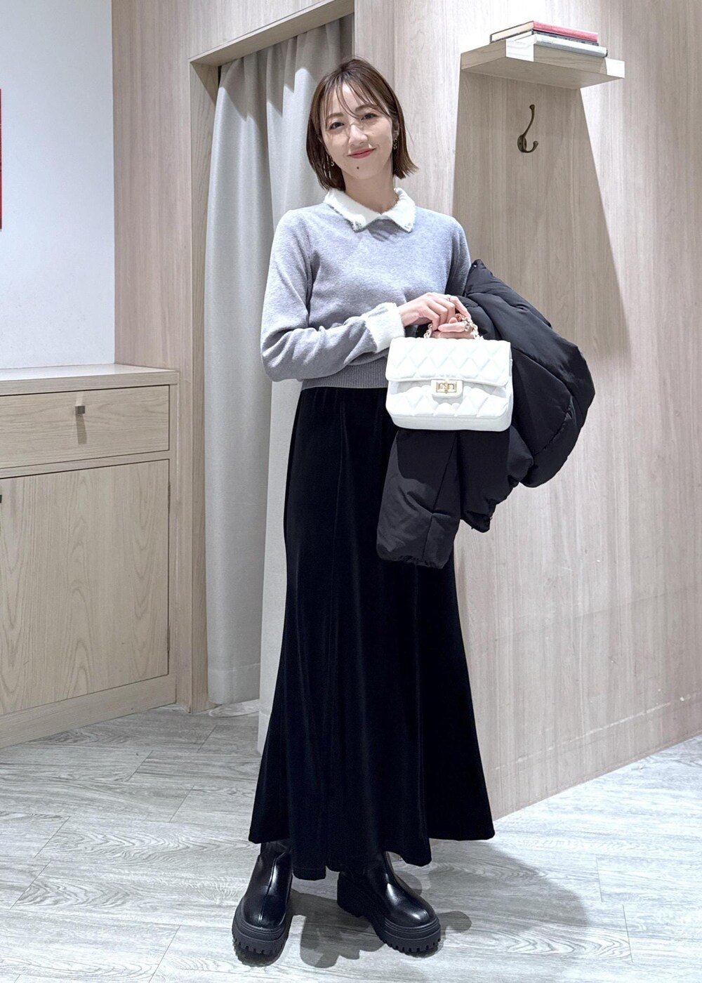 ブラック系のブーツ、ブラック系のスカート、ブラック系のダウンジャケット/コートを着用したレディースの冬コーディネートの5枚目の写真