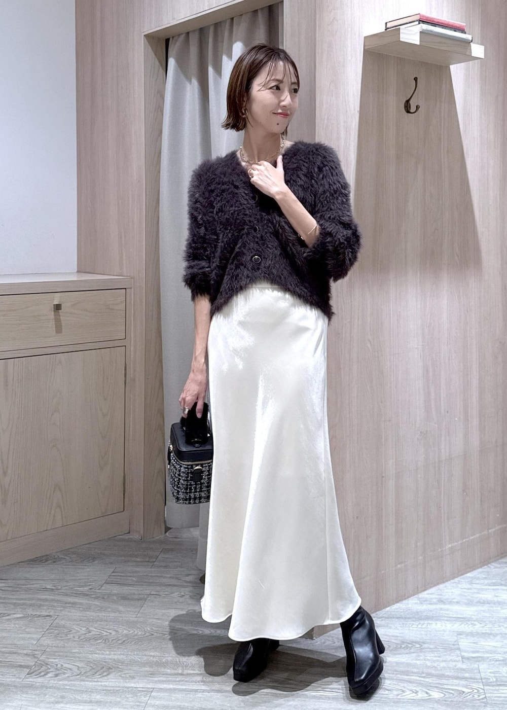 ブラック系のブーツ、ホワイト系のスカート、グレー系のカーディガン/ボレロを着用したレディースの冬コーディネートの10枚目の写真