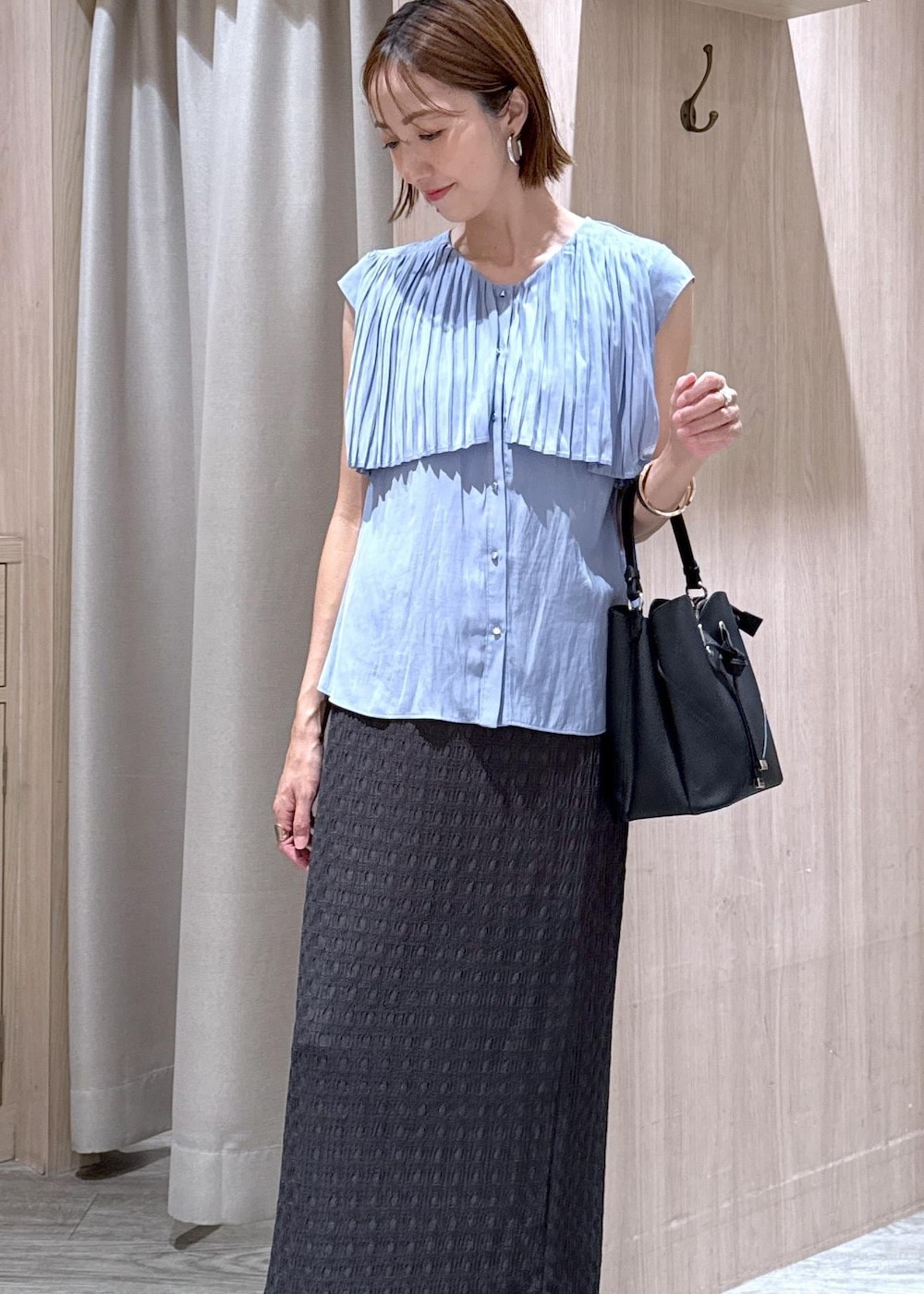 ブラック系のショルダーバッグ、ブラック系のローファー、グレー系のスカートを着用したレディースの夏コーディネートの4枚目の写真