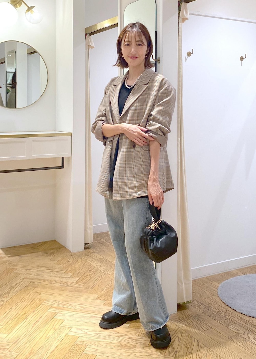 ブラック系のブーツ、ブラック系のTシャツ/カットソー、ブルー系のデニムパンツを着用したレディースの秋コーディネートの4枚目の写真