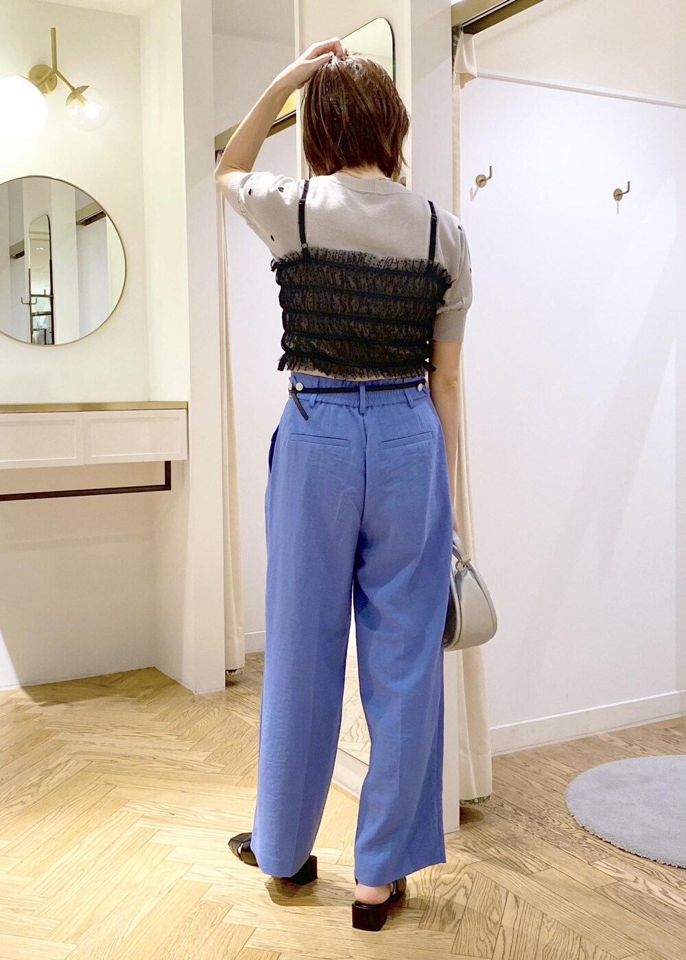 ブルー系のスラックス、シルバー系のショルダーバッグ、ブラック系のサンダルを着用したレディースの春コーディネートの2枚目の写真