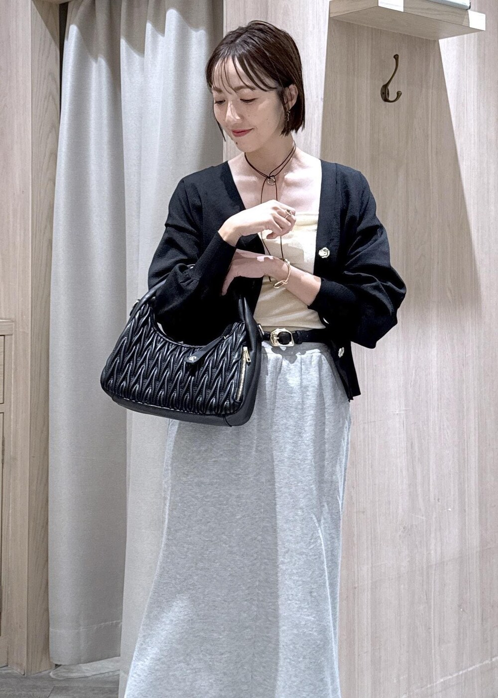 グレー系のスカート、ホワイト系のキャミソール、ブラック系のカーディガン/ボレロを着用したレディースの秋コーディネートの3枚目の写真