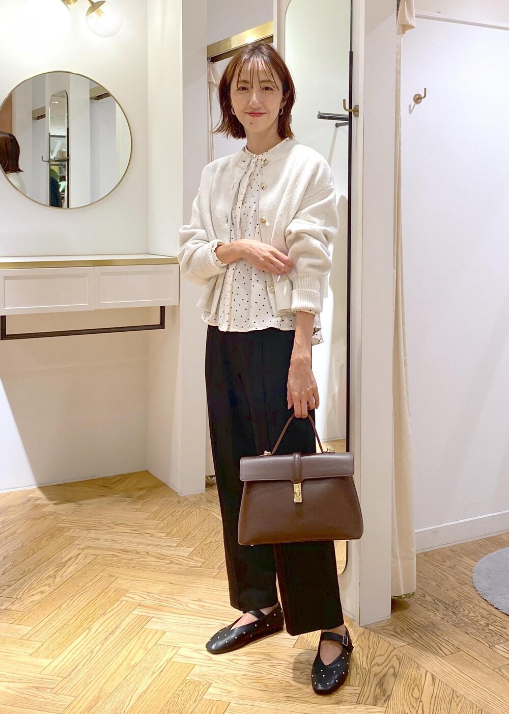 ブラウン系のハンドバッグ、ブラック系のバレエシューズ、ブラック系のスラックスを着用したレディースの秋コーディネートの9枚目の写真