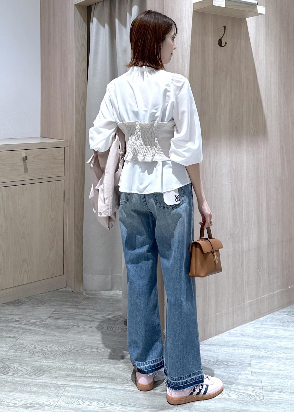 イエロー系のショルダーバッグ、ピンク系のナイロンジャケット、ブルー系のデニムパンツを着用したレディースの春コーディネートの8枚目の写真