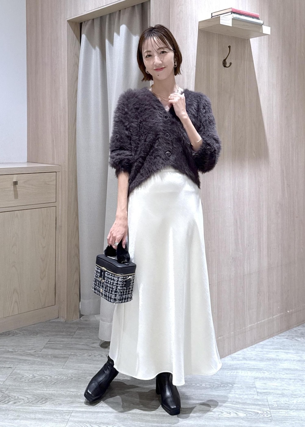 ブラック系のブーツ、ホワイト系のスカート、グレー系のカーディガン/ボレロを着用したレディースの冬コーディネートの2枚目の写真
