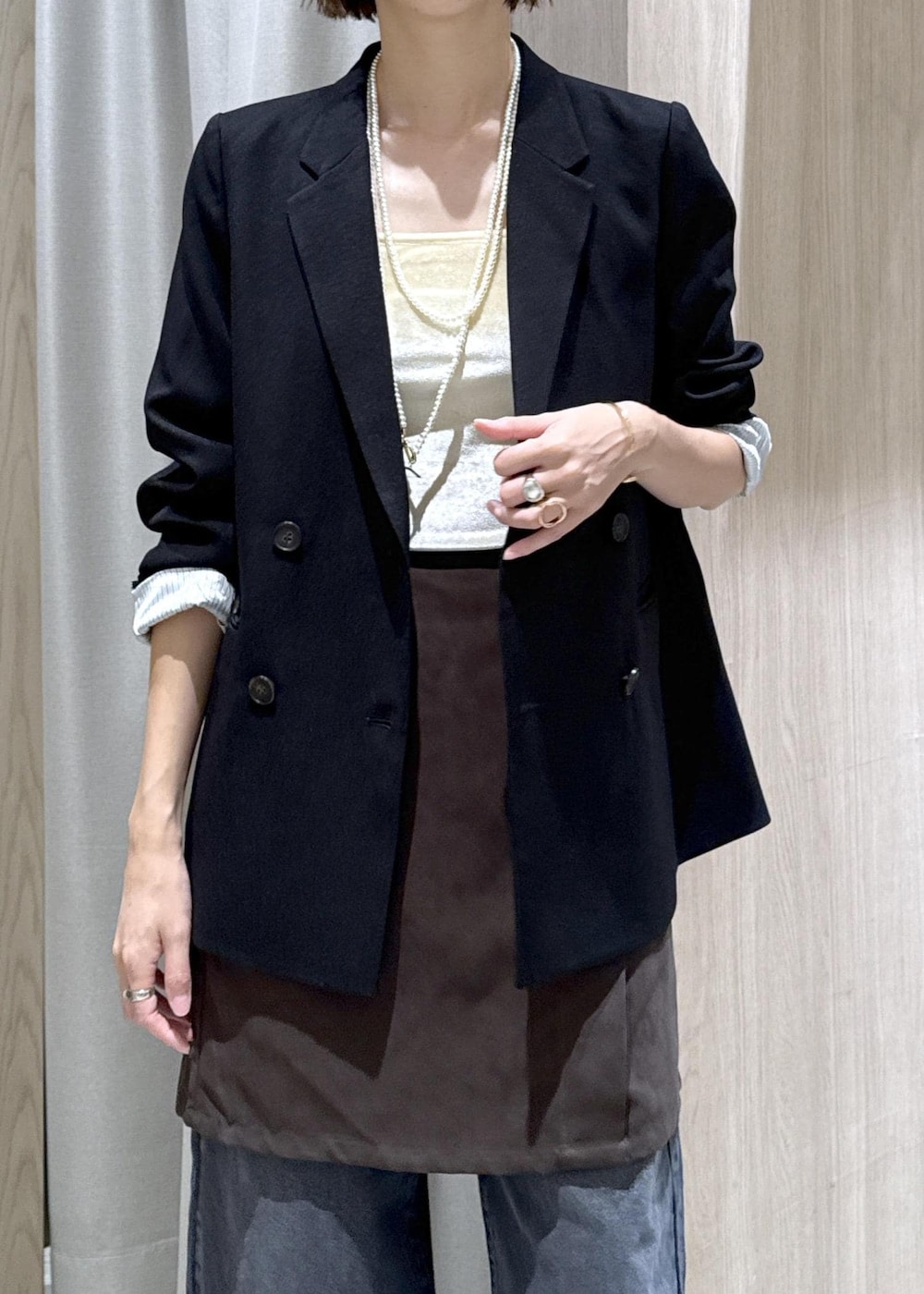 シルバー系のパンプス、ベージュ系のショルダーバッグ、ブラック系のテーラードジャケットを着用したレディースの秋コーディネートの7枚目の写真