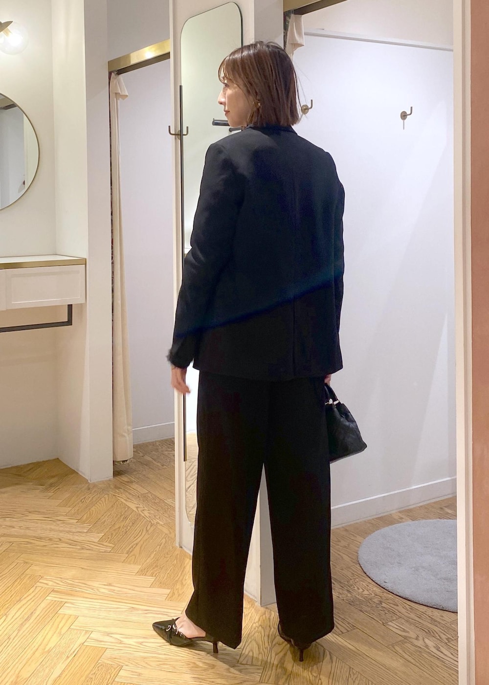 ブラック系のニット/セーター、ブラック系のスラックス、ブラック系のテーラードジャケットを着用したレディースの冬コーディネートの3枚目の写真