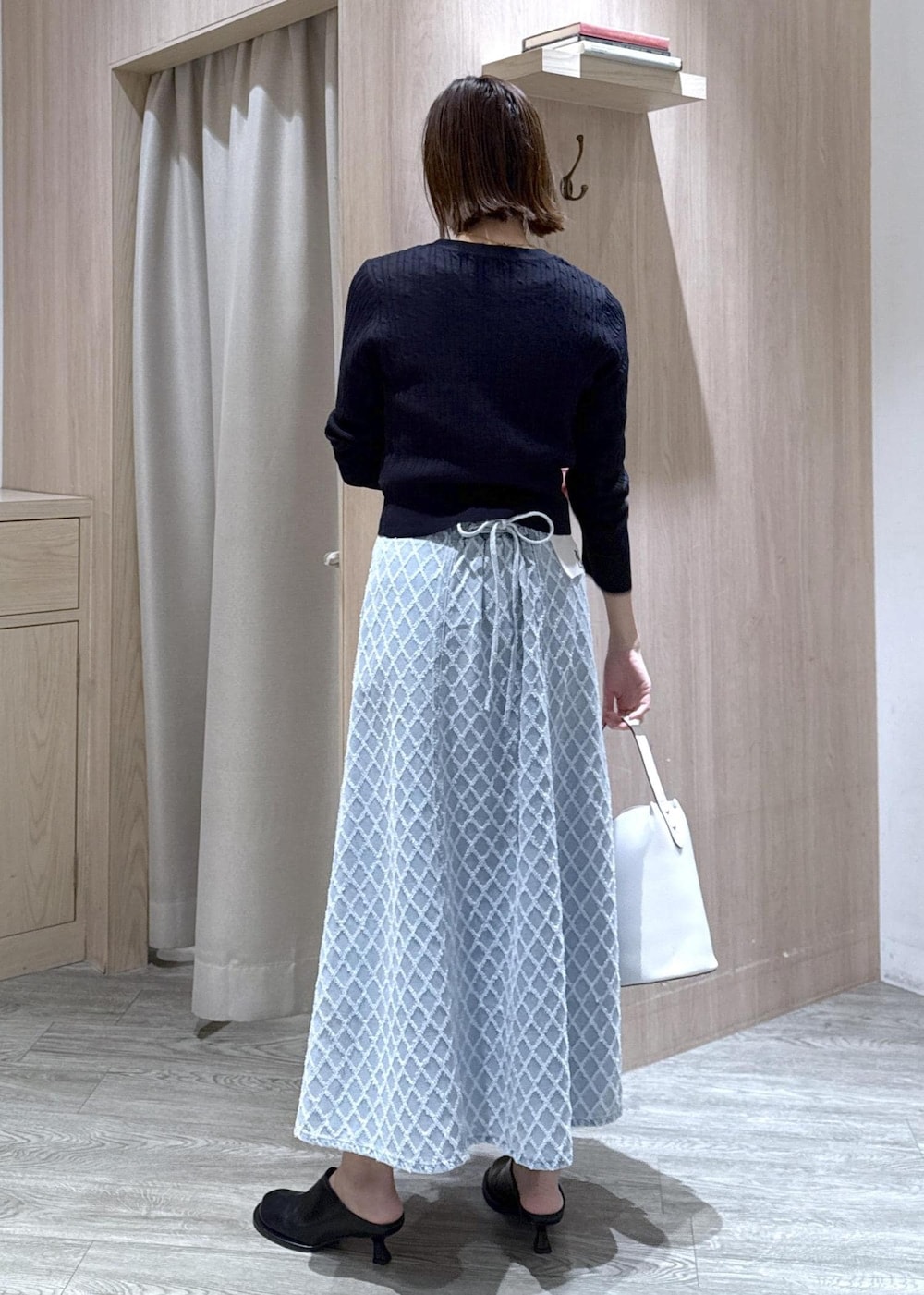 ホワイト系のショルダーバッグ、ブルー系のカーディガン/ボレロ、ブルー系のデニムスカートを着用したレディースの冬コーディネートの2枚目の写真