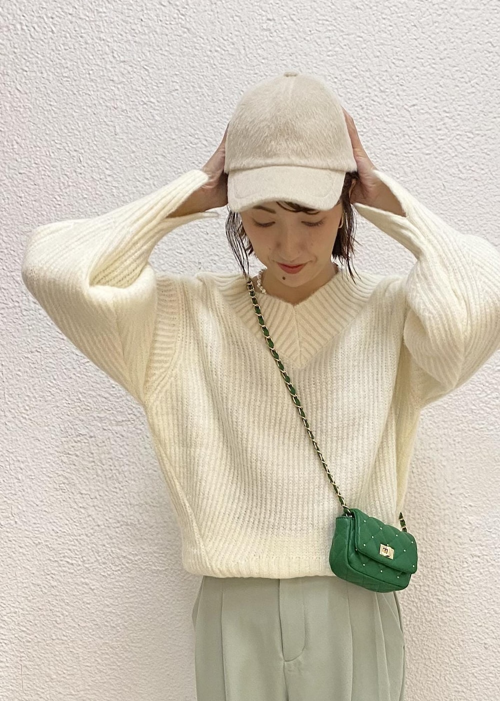 グリーン系のスラックス、グリーン系のショルダーバッグ、ホワイト系のニット/セーターを着用したレディースの冬コーディネートの5枚目の写真