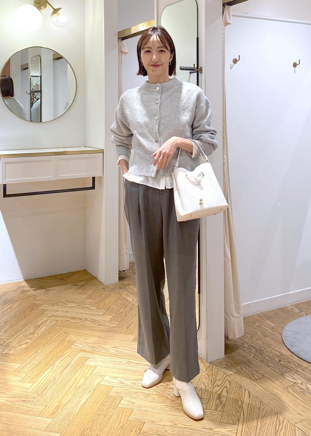 ホワイト系のブーツ、ホワイト系のシャツ/ブラウス、グレー系のカーディガン/ボレロを着用したレディースの冬コーディネートの2枚目の写真