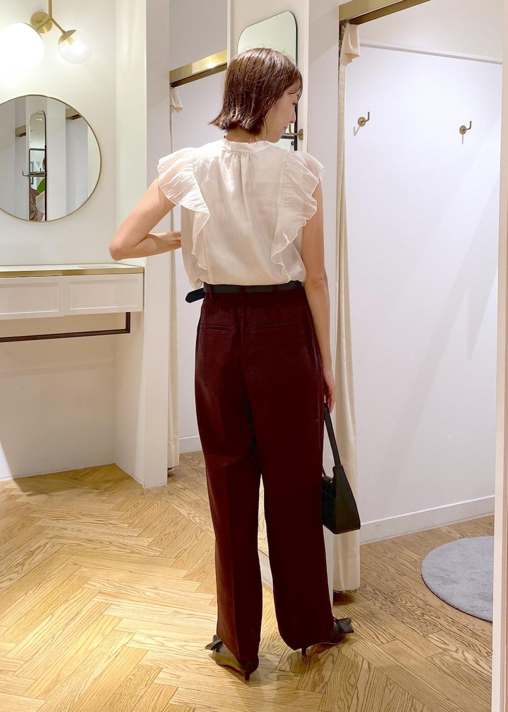 ブラック系のハンドバッグ、ブラック系のパンプス、ブラウン系のスラックスを着用したレディースの夏コーディネートの3枚目の写真