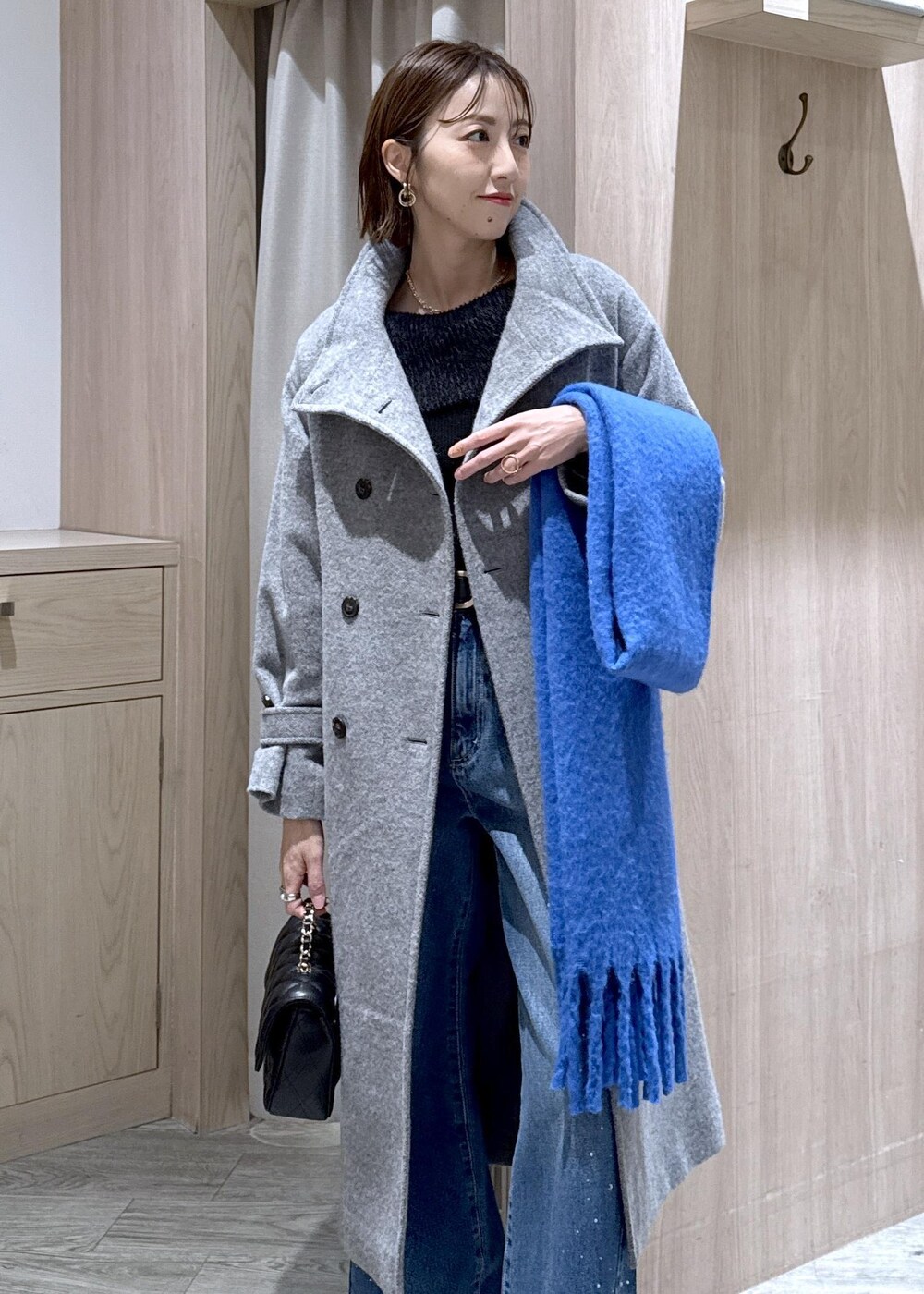 グレー系のその他アウター、ブルー系のデニムパンツ、ブラック系のニット/セーターを着用したレディースの冬コーディネートの3枚目の写真