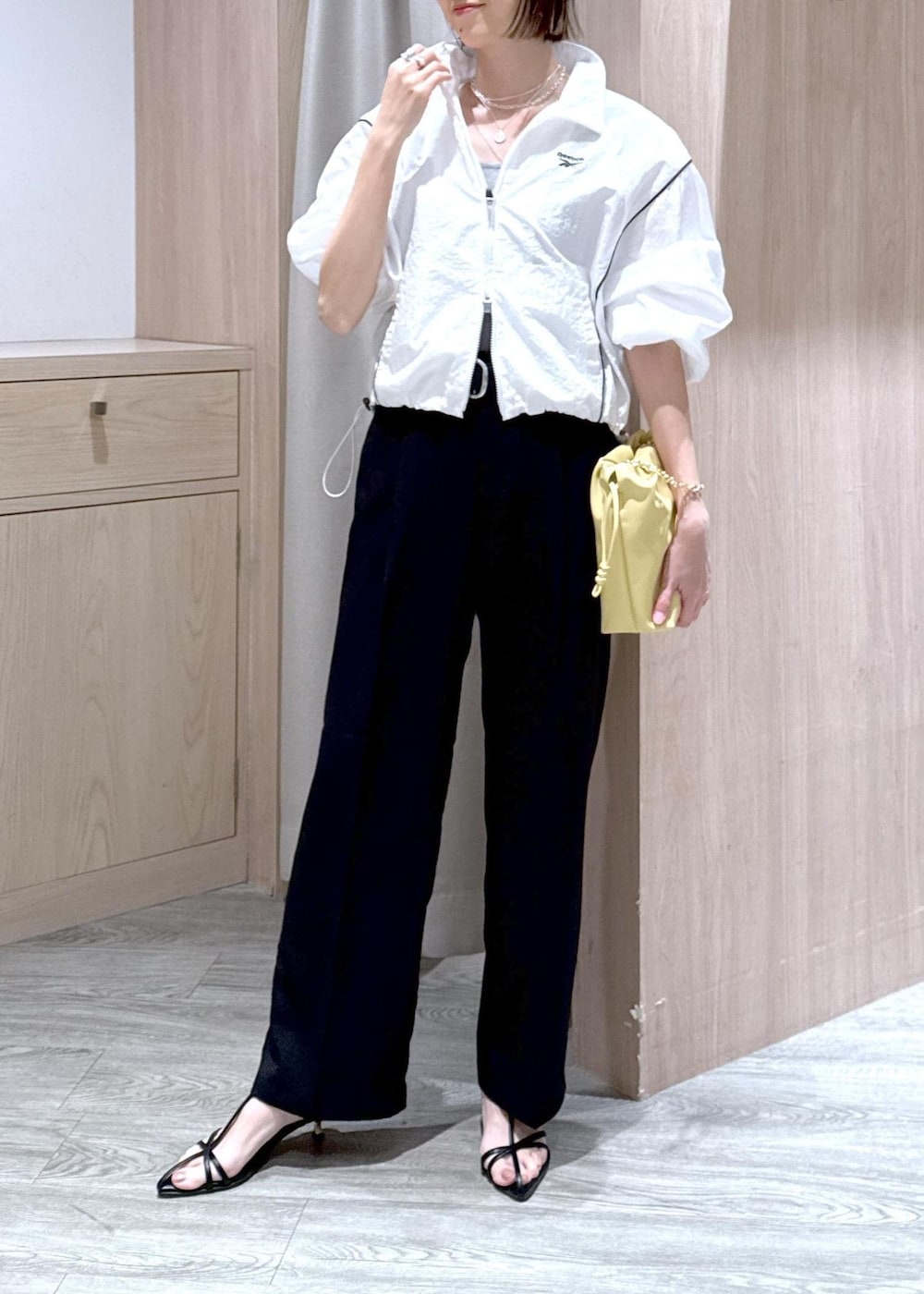 グレー系のタンクトップ、ブラック系のサンダル、ブラック系のスラックスを着用したレディースの春コーディネートの5枚目の写真