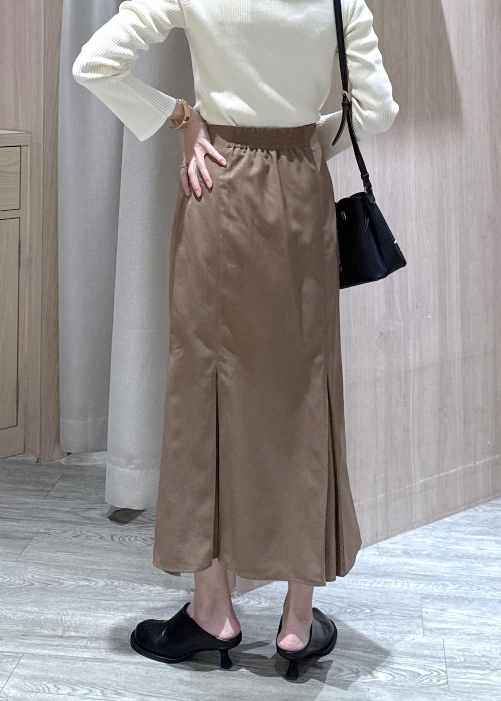 ブラウン系のスカート、ホワイト系のニット/セーター、ブラック系のショルダーバッグを着用したレディースの冬コーディネートの7枚目の写真