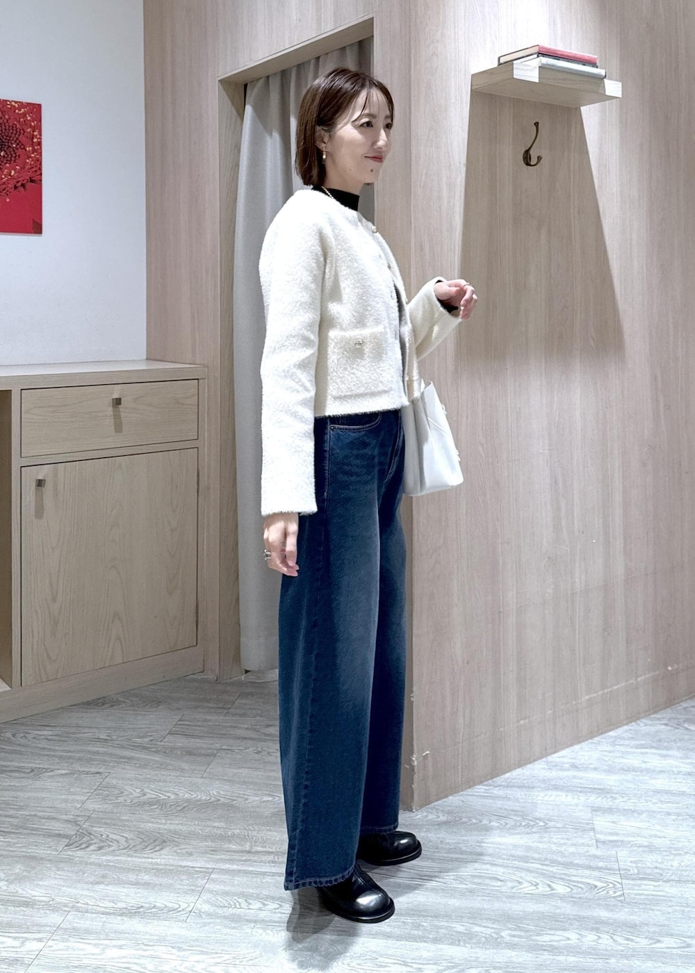 ホワイト系のショルダーバッグ、ブルー系のデニムパンツ、ブラック系のニット/セーターを着用したレディースの冬コーディネートの3枚目の写真