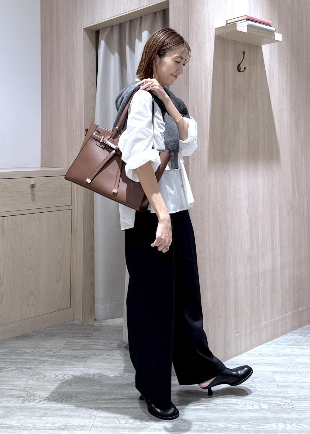 ブラウン系のトートバッグ、ホワイト系のシャツ/ブラウス、ブラック系のスラックスを着用したレディースの秋コーディネートの2枚目の写真