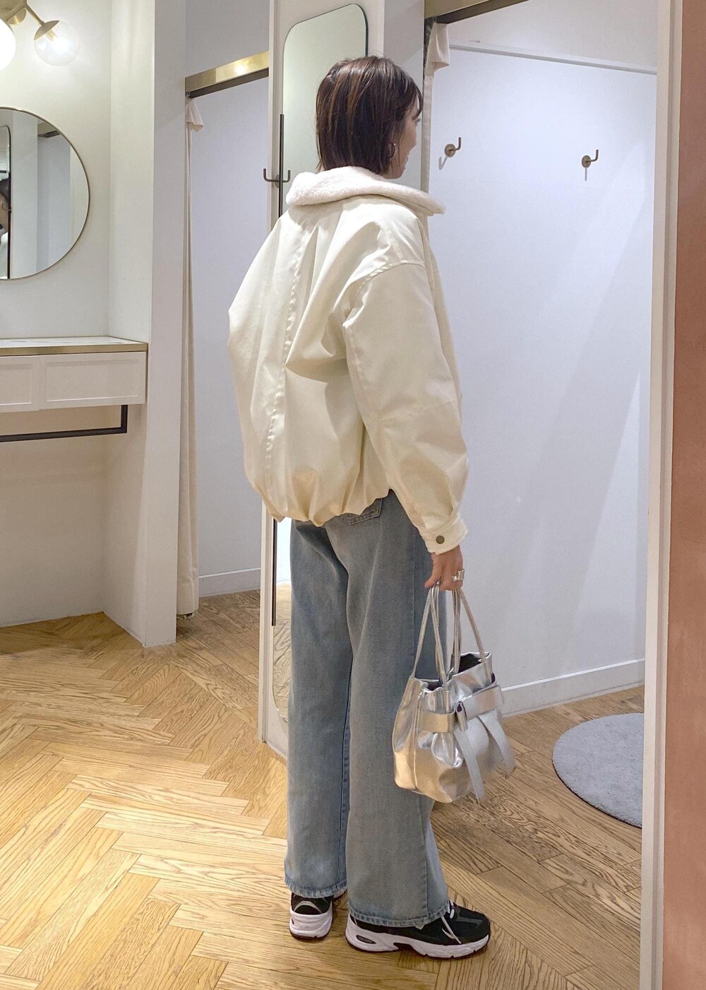 シルバー系のショルダーバッグ、ブルー系のデニムパンツ、グレー系のカーディガン/ボレロを着用したレディースの冬コーディネートの5枚目の写真