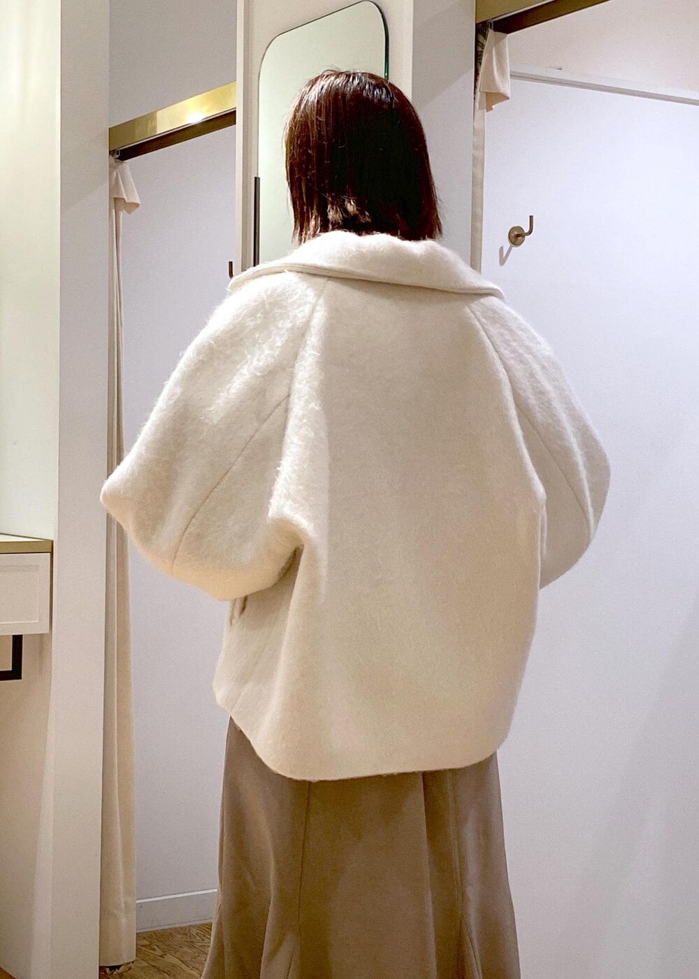 ホワイト系のブーツ、ベージュ系のスカート、ホワイト系のその他アウターを着用したレディースの秋コーディネートの7枚目の写真