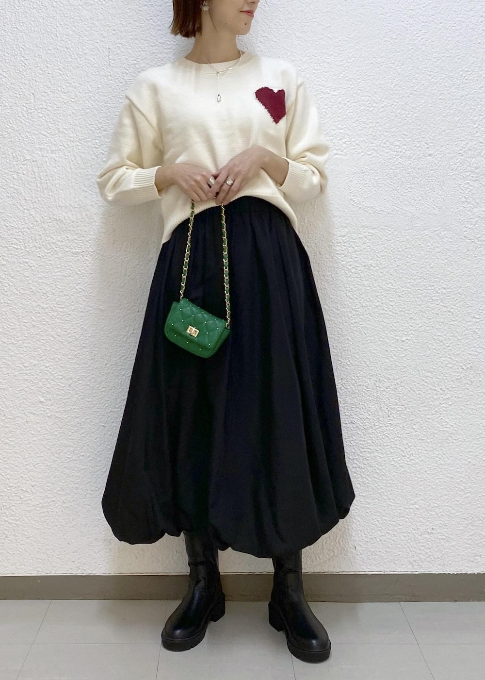 ブラック系のブーツ、ブラック系のスカート、グリーン系のショルダーバッグを着用したレディースの冬コーディネートの4枚目の写真