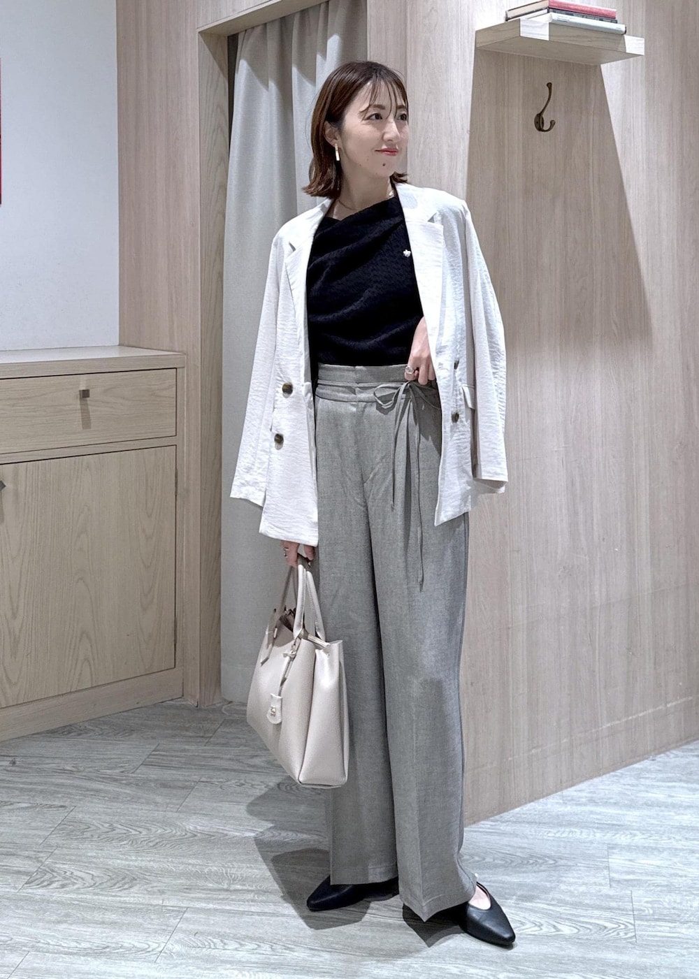 ブラック系のパンプス、グレー系のその他パンツ、ホワイト系のテーラードジャケットを着用したレディースの春コーディネートの3枚目の写真