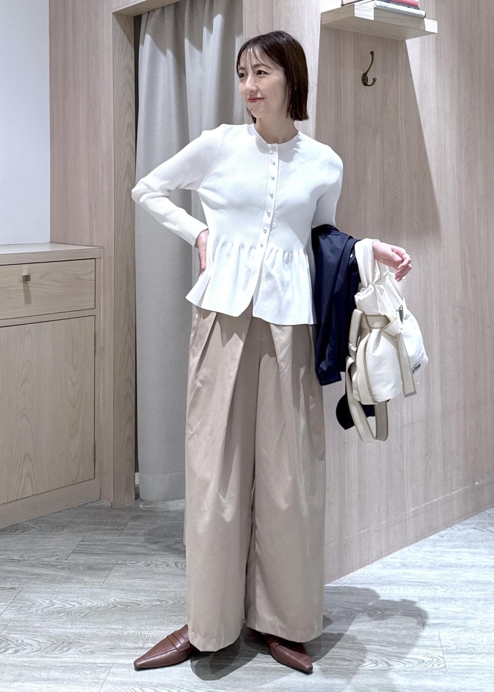 ホワイト系のカーディガン/ボレロ、ホワイト系のトートバッグ、ブルー系のナイロンジャケットを着用したレディースの春コーディネートの8枚目の写真