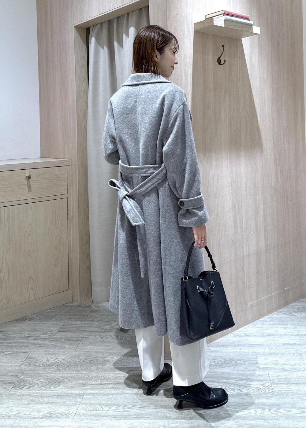 ブラック系のショルダーバッグ、グレー系のその他アウター、ホワイト系のスラックスを着用したレディースの冬コーディネートの5枚目の写真