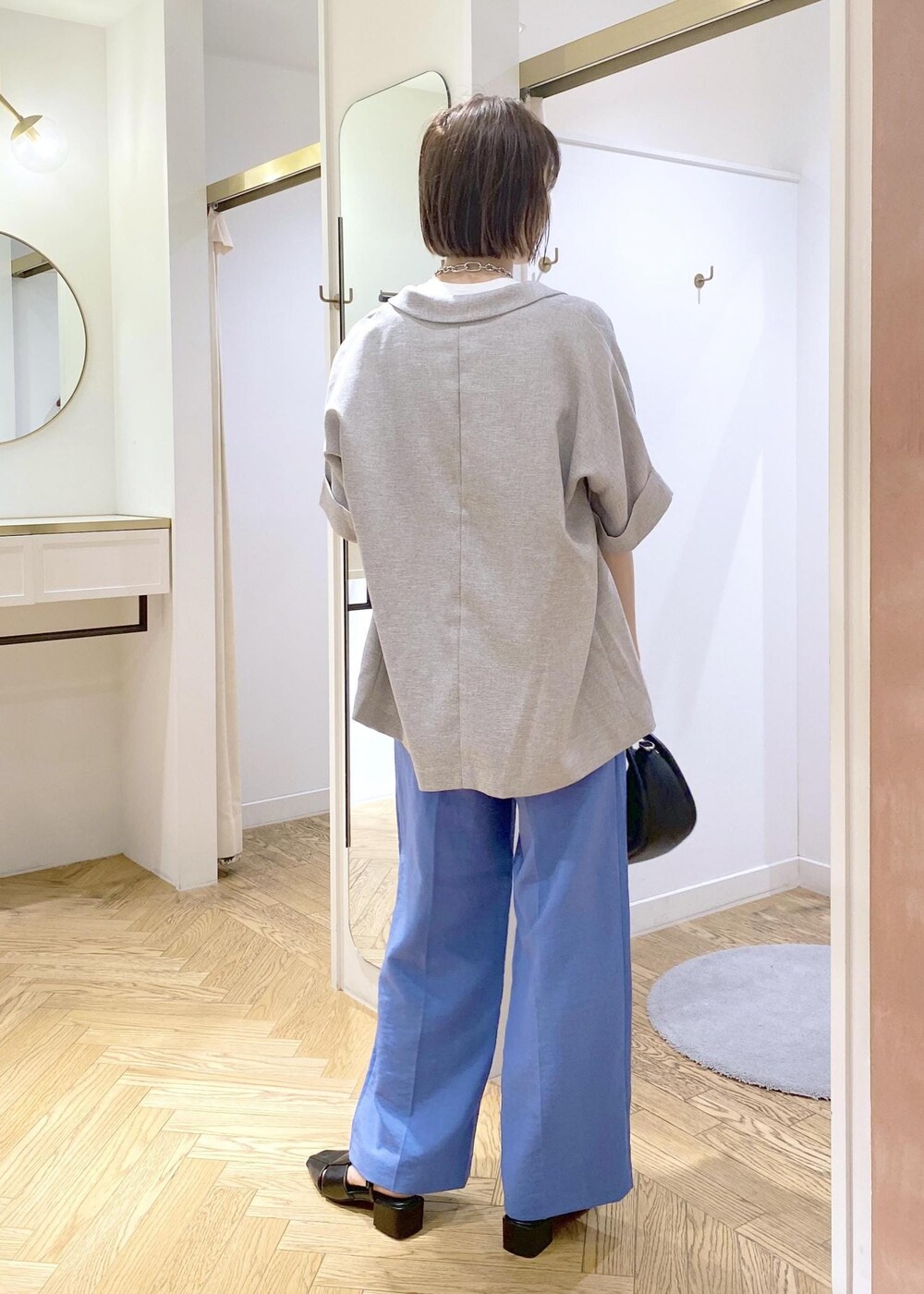 ブルー系のスラックス、ブラック系のショルダーバッグ、ブラック系のサンダルを着用したレディースの春コーディネートの4枚目の写真