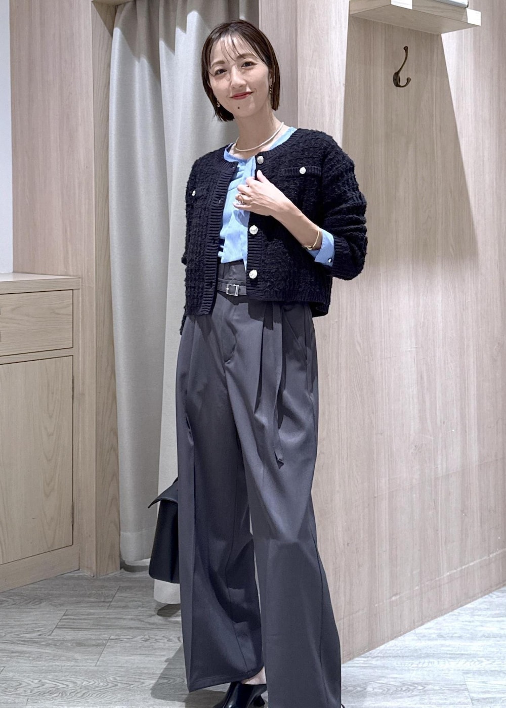 ブラック系のハンドバッグ、ブルー系のカーディガン/ボレロ、グレー系のその他パンツを着用したレディースの秋コーディネートの2枚目の写真