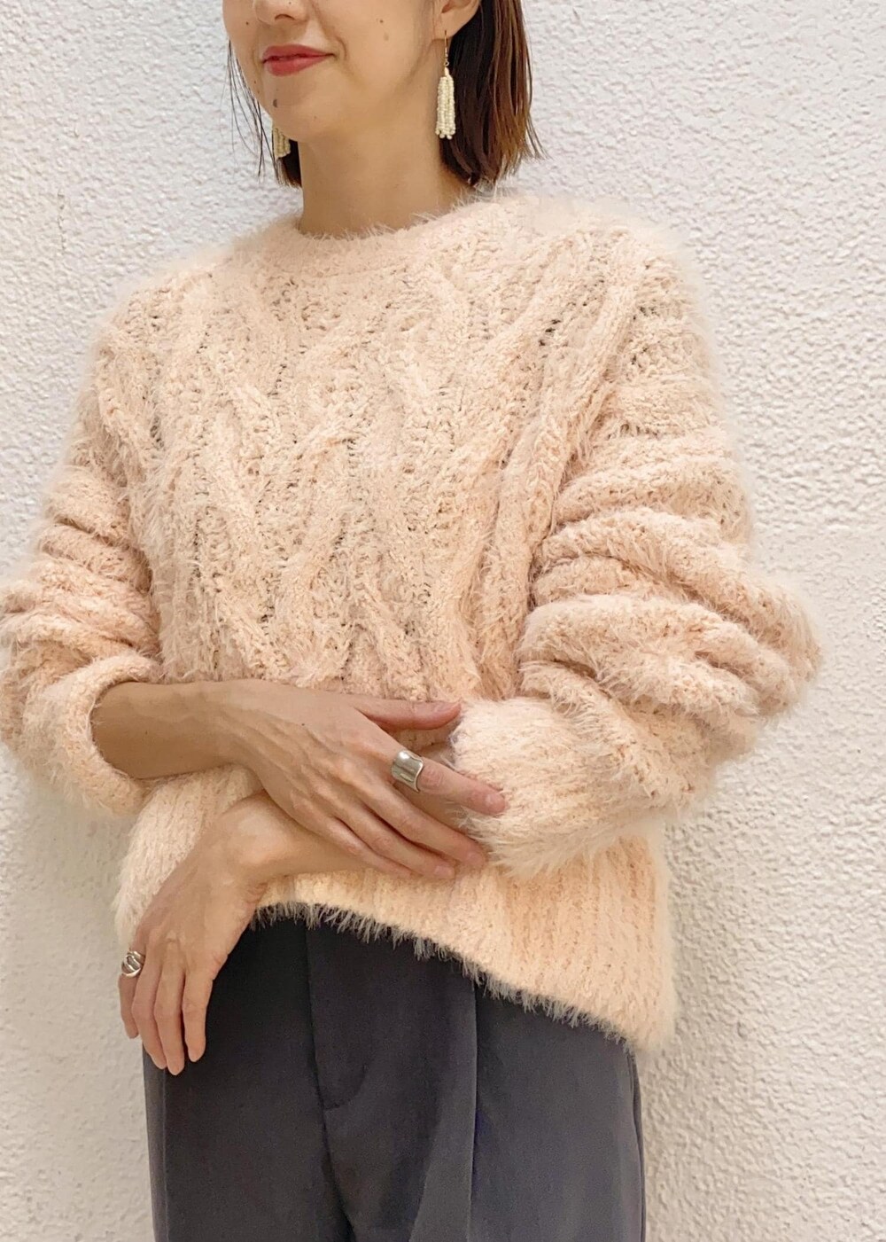 ホワイト系のショルダーバッグ、ピンク系のニット/セーター、グレー系のスラックスを着用したレディースの冬コーディネートの4枚目の写真