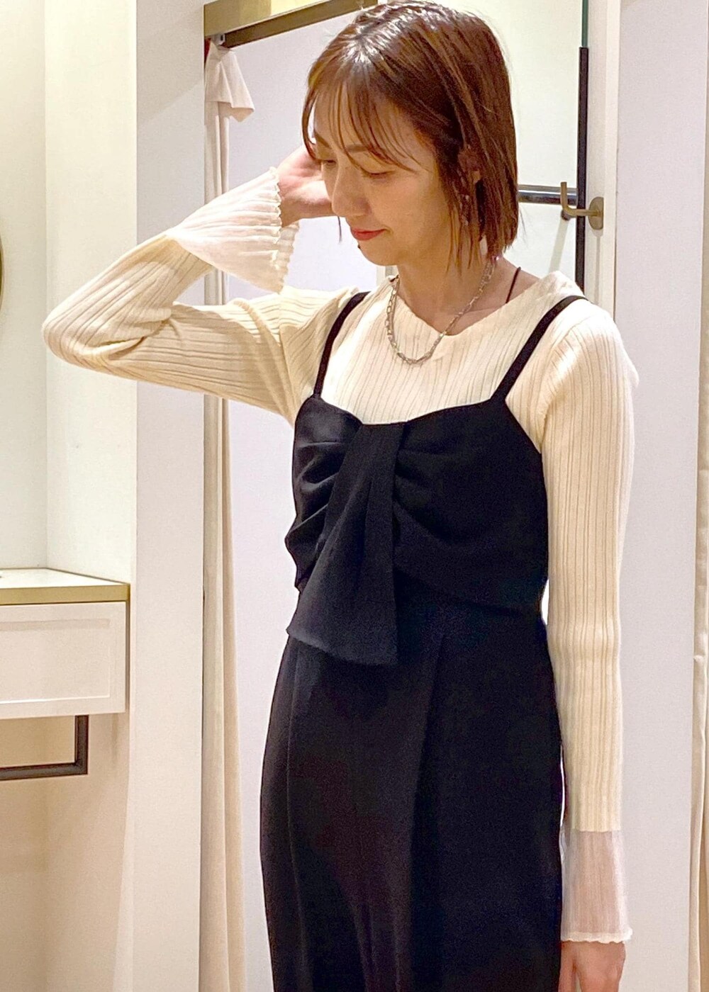 グレー系のショルダーバッグ、ブラック系のサロペット/オーバーオール、ホワイト系のニット/セーターを着用したレディースの冬コーディネートの7枚目の写真