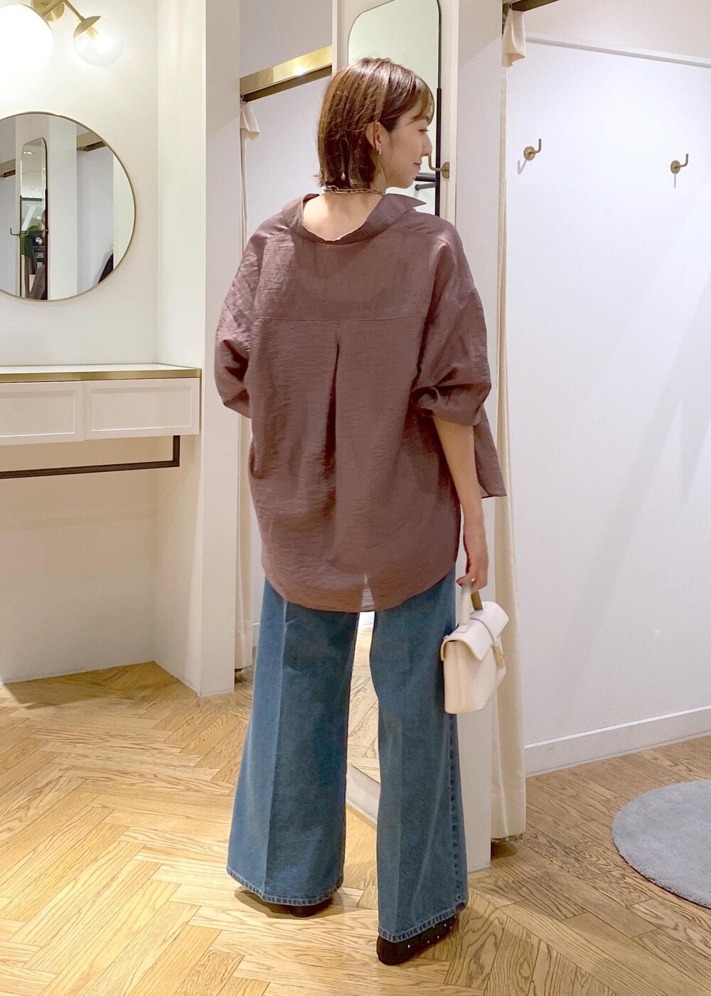 ブラック系のキャミソール、ホワイト系のショルダーバッグ、ブルー系のデニムパンツを着用したレディースの秋コーディネートの3枚目の写真