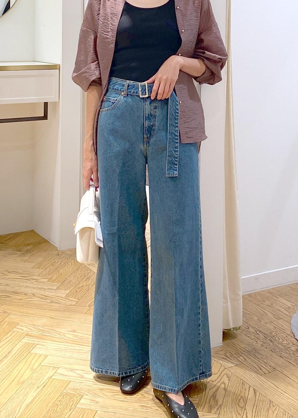 ブラック系のキャミソール、ホワイト系のショルダーバッグ、ブルー系のデニムパンツを着用したレディースの秋コーディネートの5枚目の写真