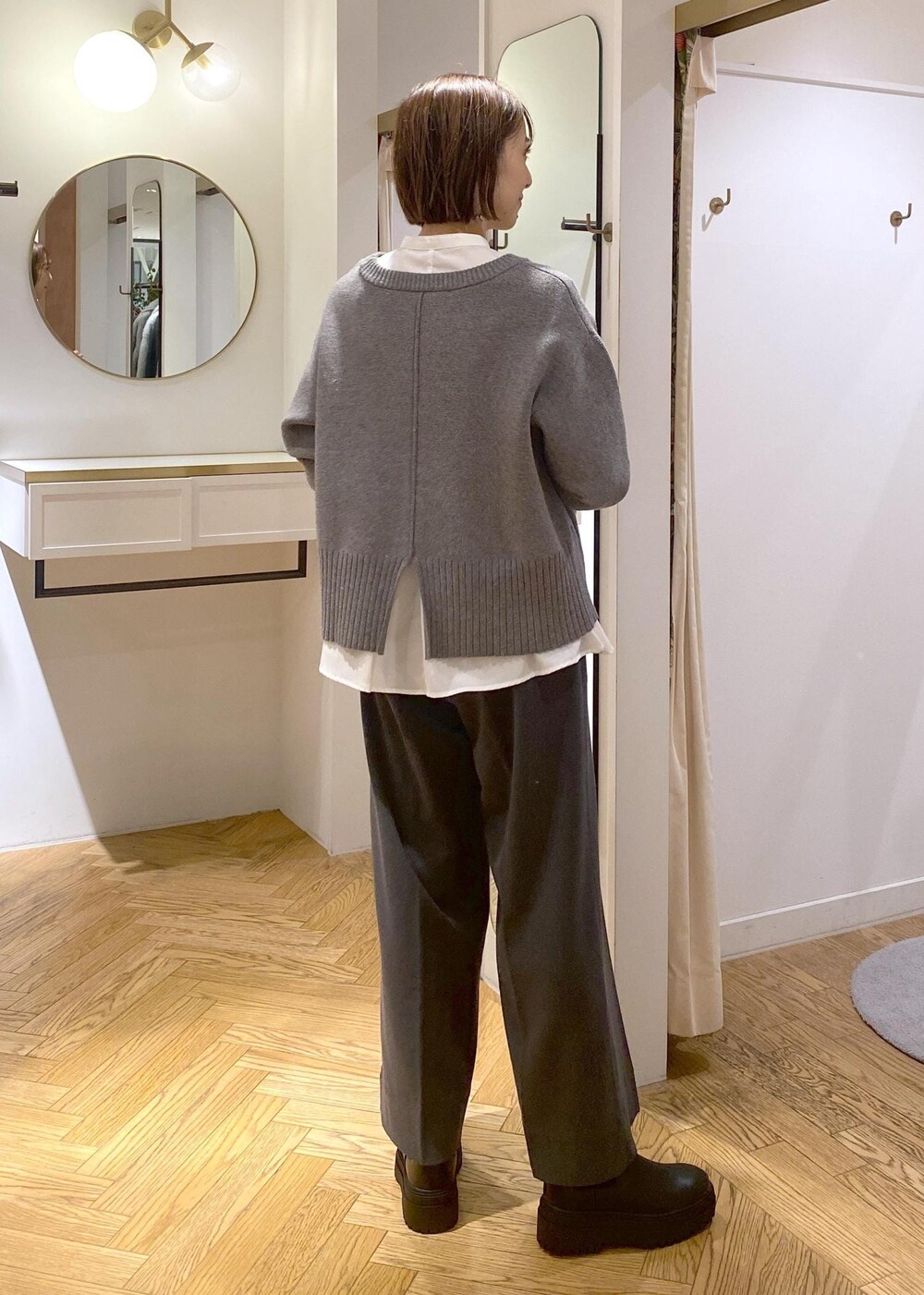 ブラック系のブーツ、ホワイト系のシャツ/ブラウス、グレー系のニット/セーターを着用したレディースの冬コーディネートの2枚目の写真