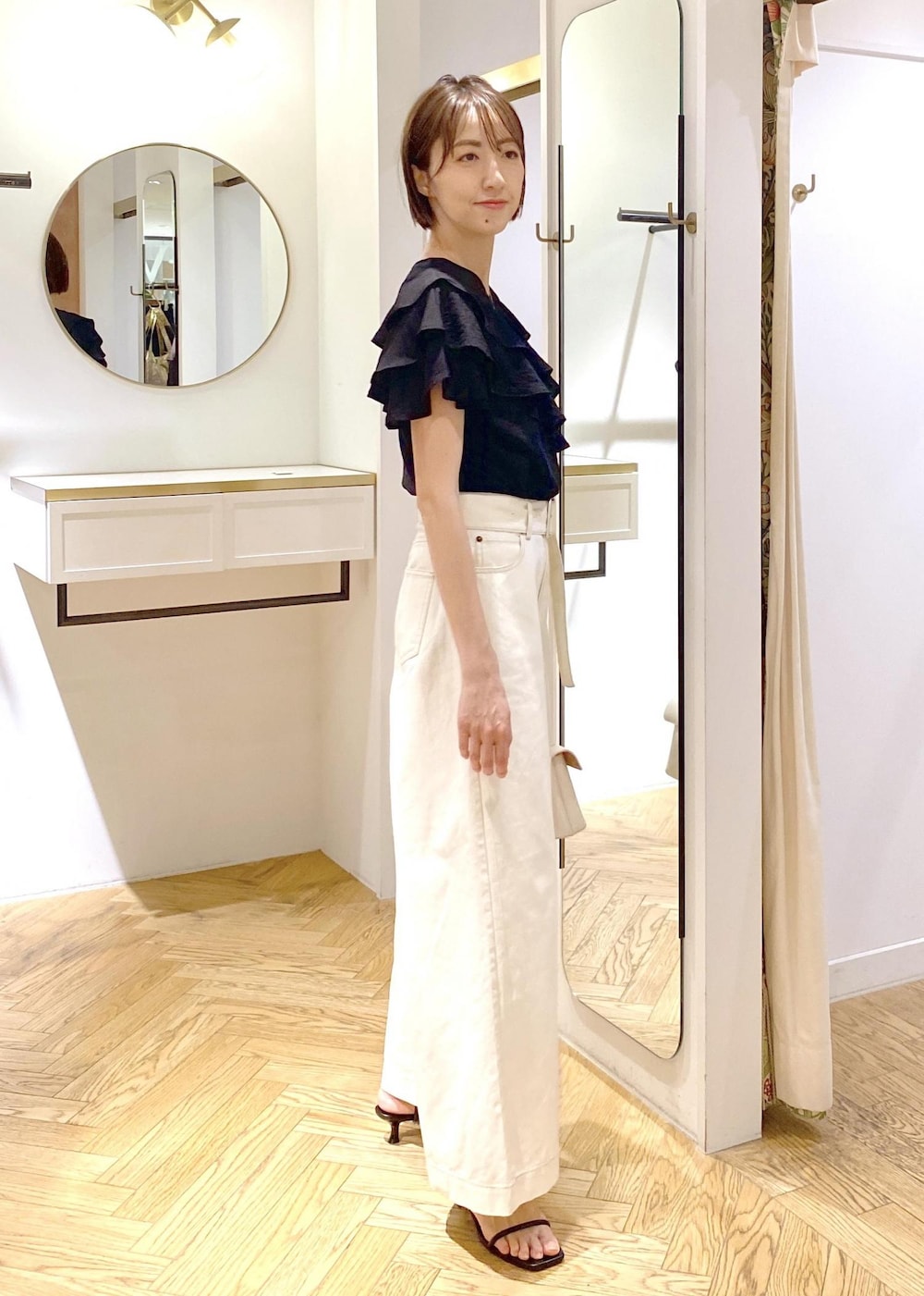 ホワイト系のショルダーバッグ、ブラック系のシャツ/ブラウス、ホワイト系のデニムパンツを着用したレディースの夏コーディネートの2枚目の写真