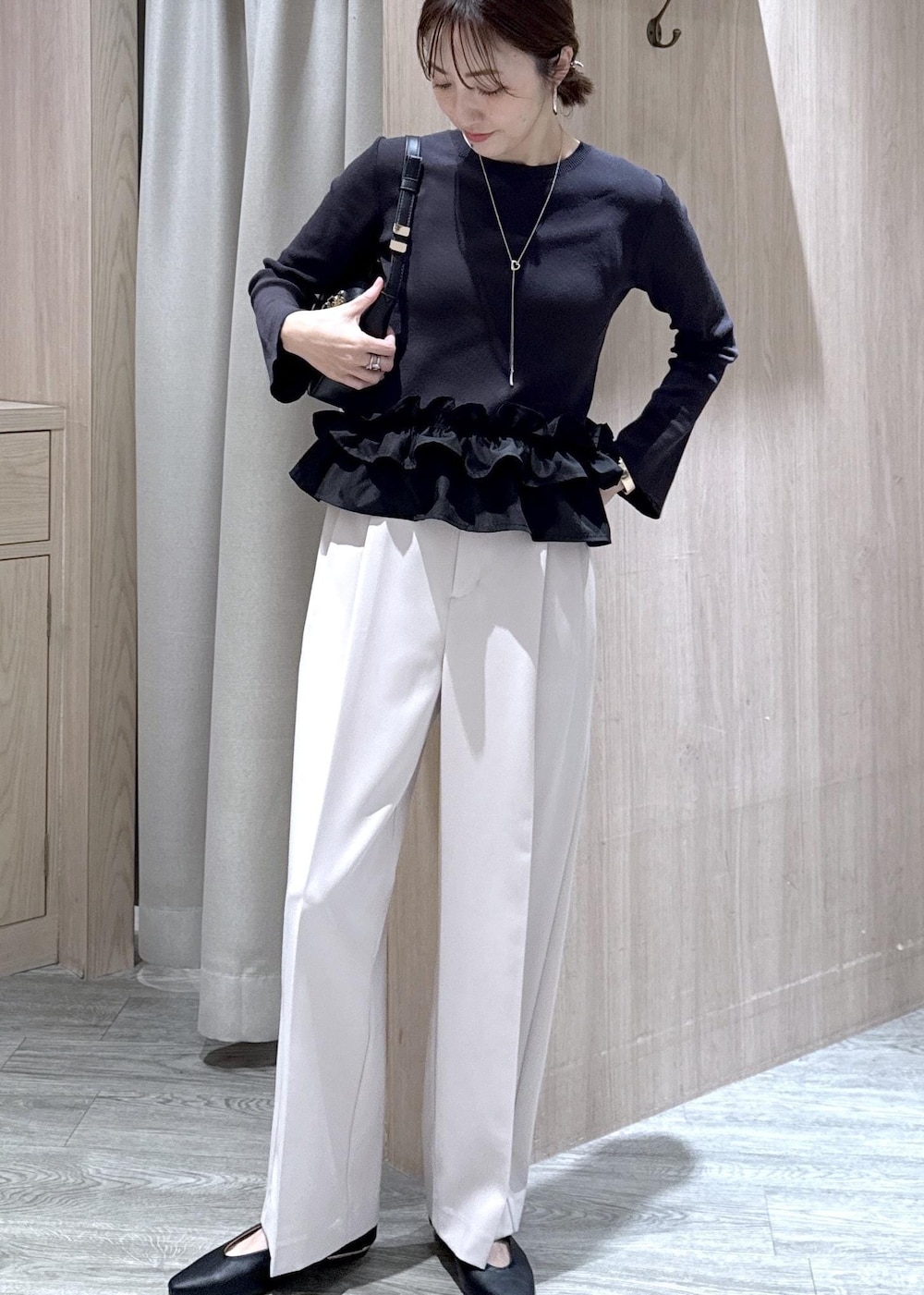 ブラック系のショルダーバッグ、ブラック系のパンプス、グレー系のニット/セーターを着用したレディースの春コーディネートの3枚目の写真