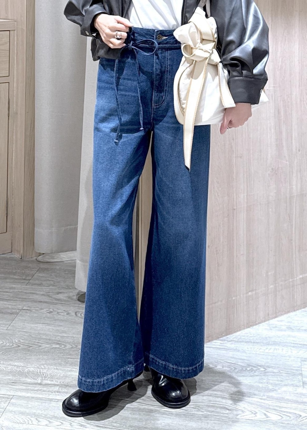 ホワイト系のトートバッグ、ブラック系のブルゾン、ホワイト系のTシャツ/カットソーを着用したレディースの冬コーディネートの4枚目の写真