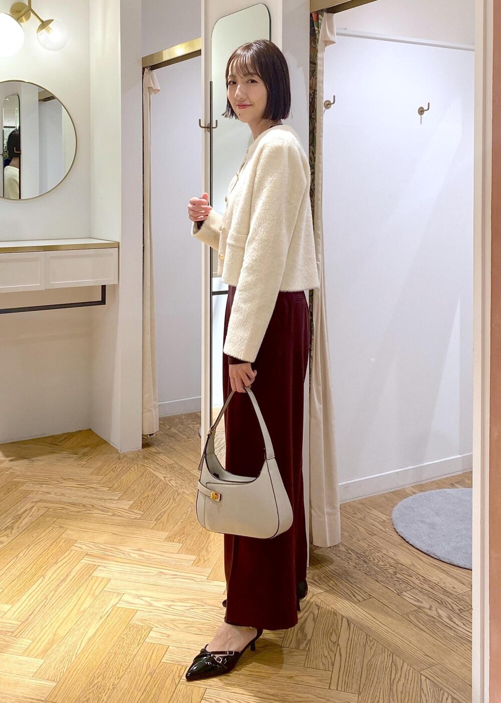 ホワイト系のハンドバッグ、ブラック系のパンプス、ブラウン系のその他パンツを着用したレディースの冬コーディネートの4枚目の写真