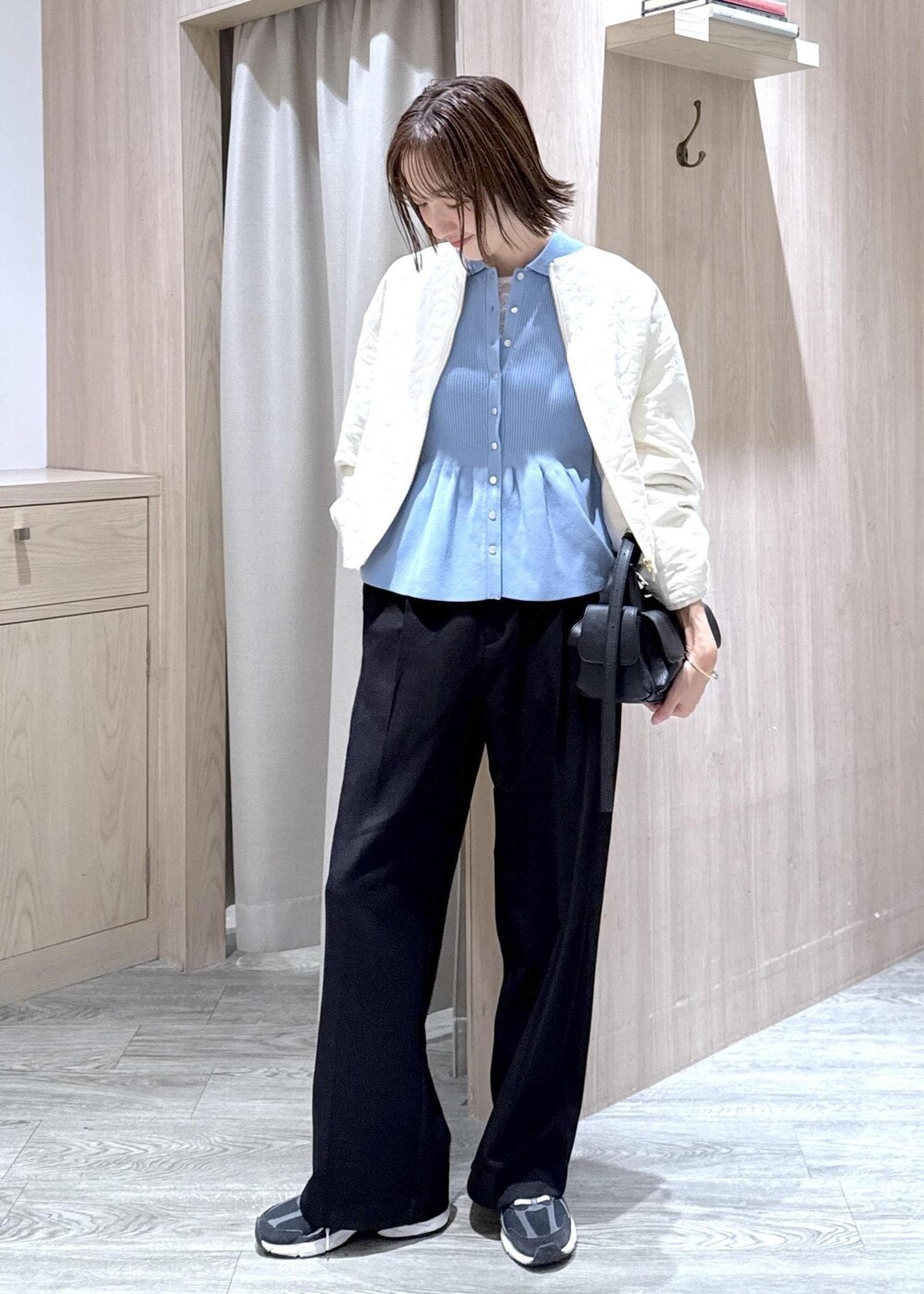 ブラック系のスラックス、ブラック系のショルダーバッグ、ブルー系のカーディガン/ボレロを着用したレディースの秋コーディネートの5枚目の写真