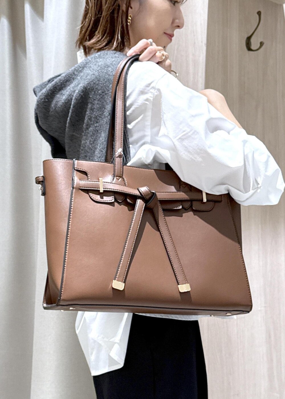 ブラウン系のトートバッグ、ホワイト系のシャツ/ブラウス、ブラック系のスラックスを着用したレディースの秋コーディネートの3枚目の写真