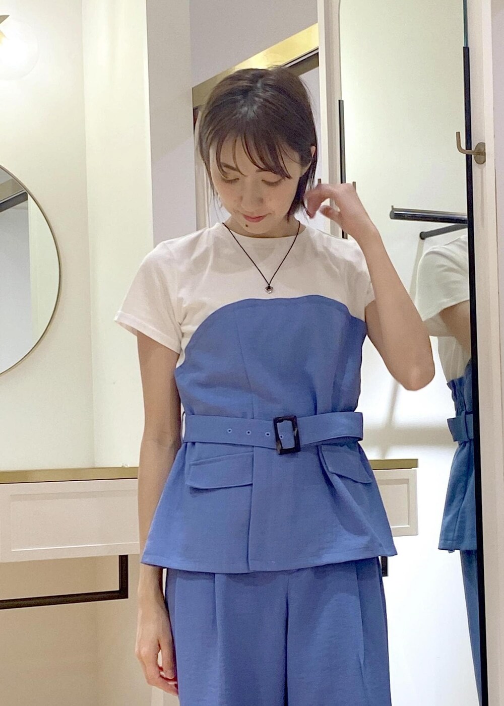 シルバー系のハンドバッグ、シルバー系のパンプス、ブルー系のTシャツ/カットソーを着用したレディースの春コーディネートの4枚目の写真