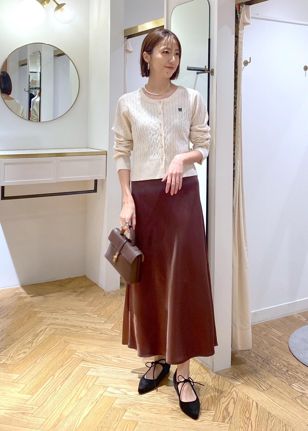 ブラウン系のスカート、ホワイト系のカーディガン/ボレロ、ブラック系のパンプスを着用したレディースの冬コーディネートの8枚目の写真