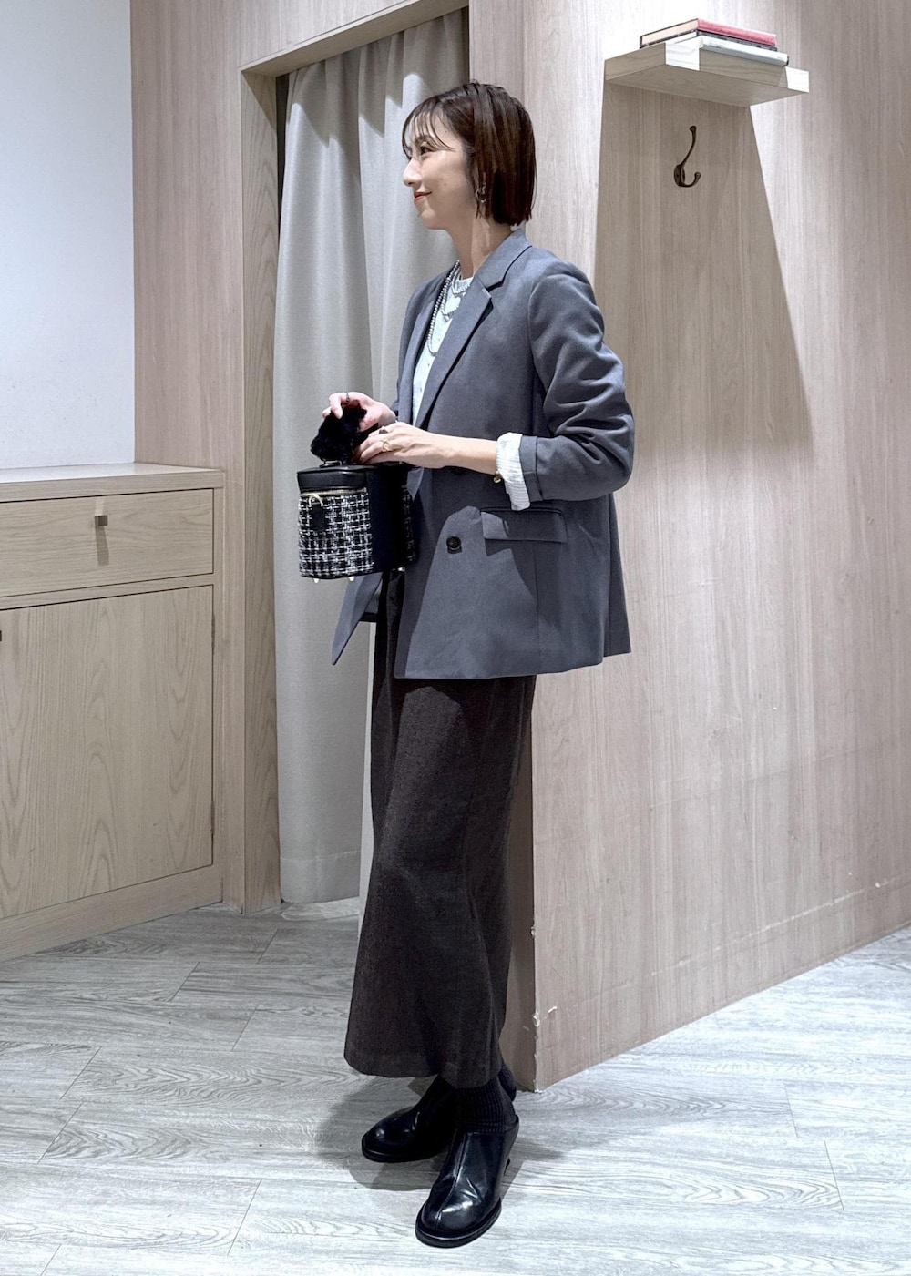 グレー系のテーラードジャケット、ブルー系のカーディガン/ボレロ、ブラウン系のスカートを着用したレディースの秋コーディネートの2枚目の写真
