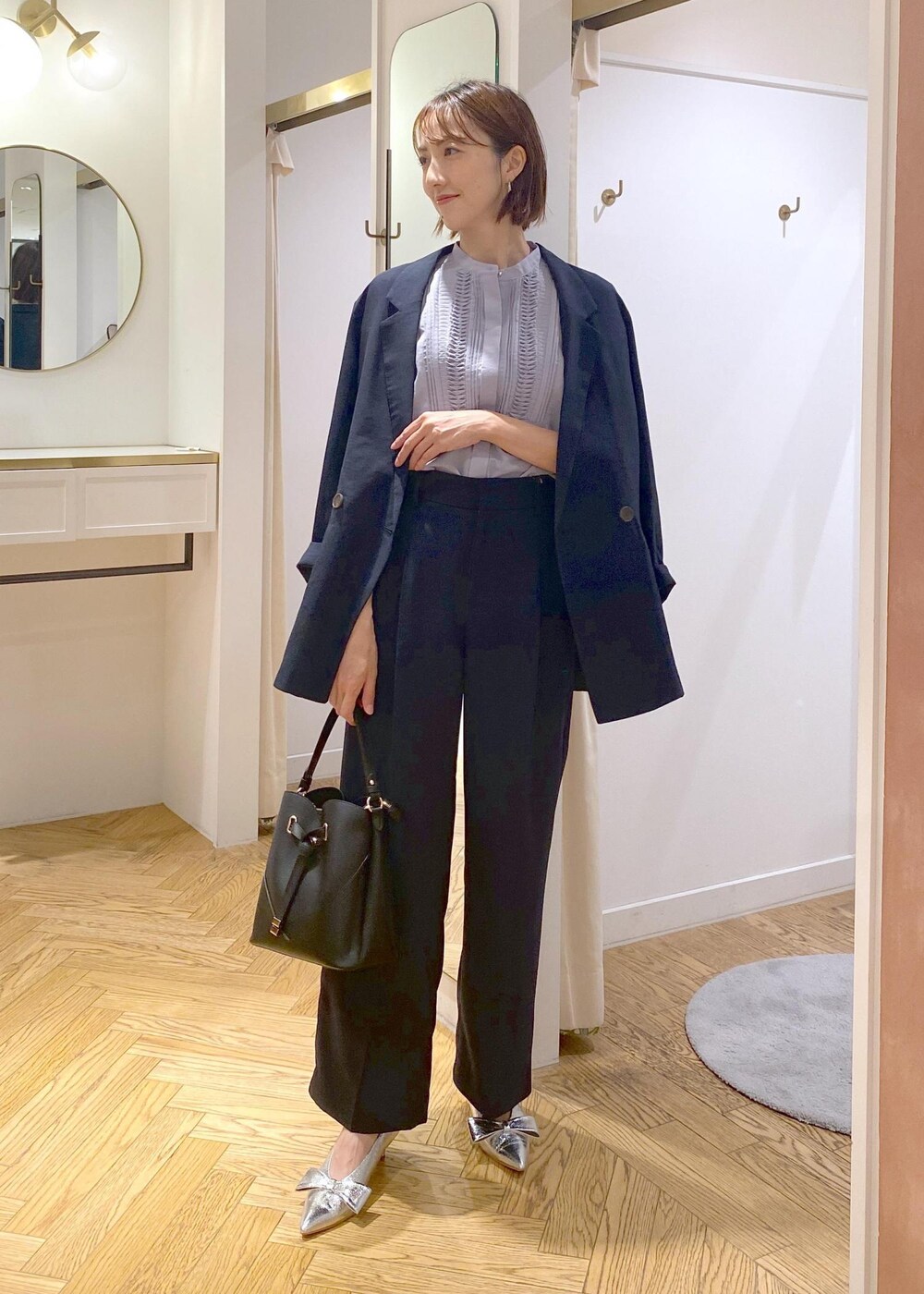 シルバー系のパンプス、ブルー系のスラックス、ブルー系のテーラードジャケットを着用したレディースの夏コーディネートの2枚目の写真