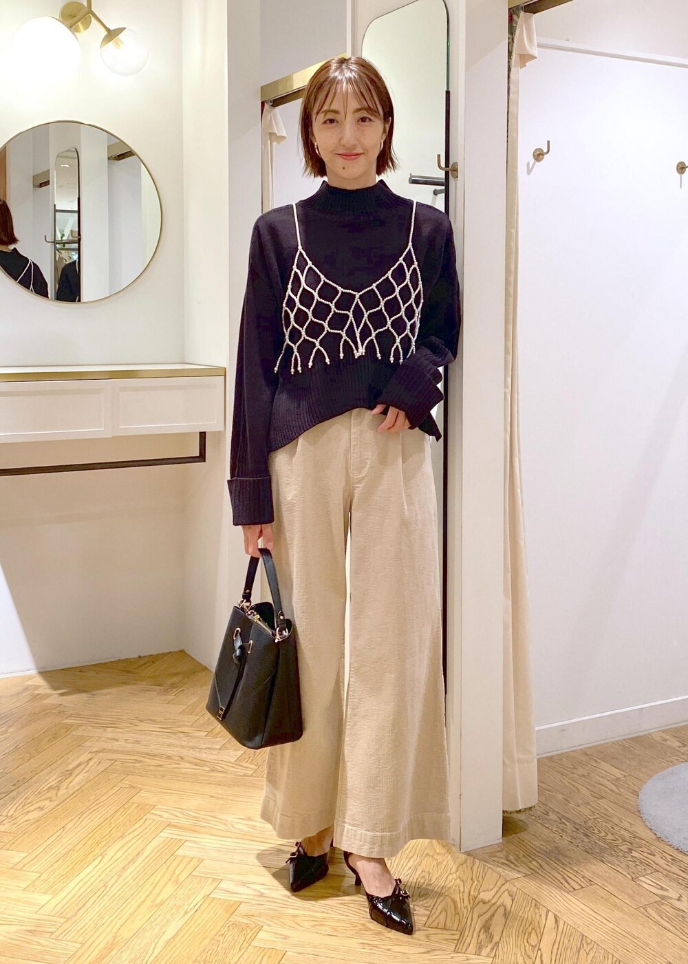 ブラック系のショルダーバッグ、ホワイト系のキャミソール、ベージュ系のスラックスを着用したレディースの秋コーディネートの8枚目の写真